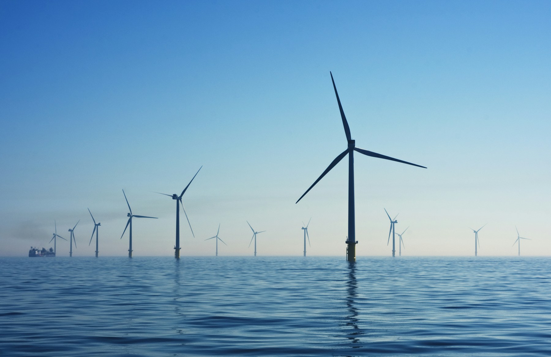 Offshore wind turbines standing in calm open water under a clear sky
